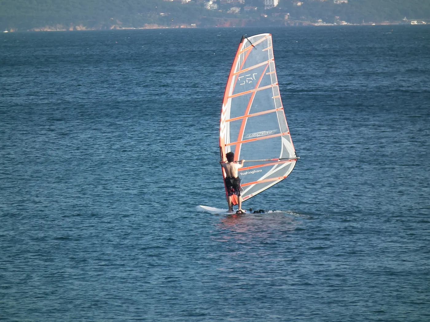 Windsurfer silhouette on open water